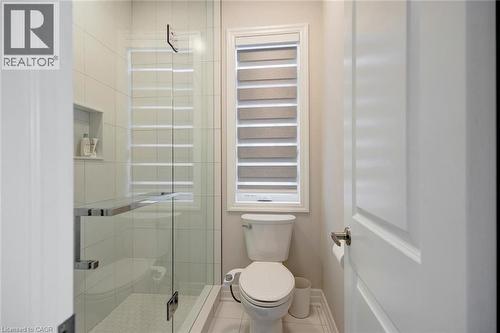 Glass-enclosed shower featuring white subway tile, a recessed shower niche, and a contrasting small hexagonal tile shower floor - 57 Hollybrook Trail, Kitchener, ON 