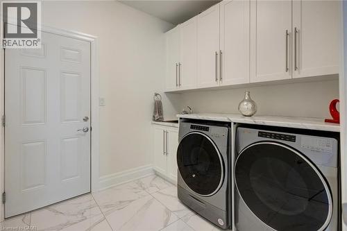Dedicated laundry area featuring white cabinetry, a built-in sink, and a countertop - 57 Hollybrook Trail, Kitchener, ON 