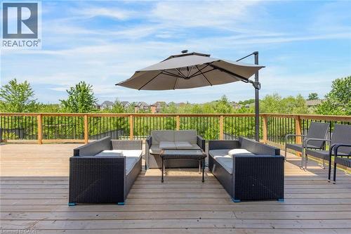 Expansive wooden deck featuring horizontal planking and a natural wood railing with black metal balusters - 57 Hollybrook Trail, Kitchener, ON 