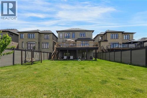 Expansive grassy backyard featuring a multi-level composite deck, ground-level patio, and a privacy fence - 57 Hollybrook Trail, Kitchener, ON 