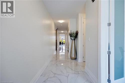 Bright, long hallway with white walls and a white marble-patterned tile floor - 57 Hollybrook Trail, Kitchener, ON 