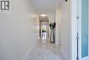 Bright, long hallway with white walls and a white marble-patterned tile floor - 57 Hollybrook Trail, Kitchener, ON 