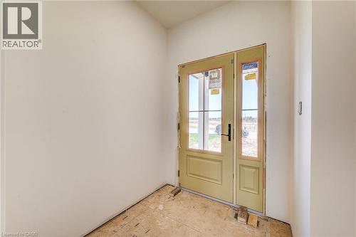 Entryway featuring a single-panel door with glass inserts and an adjacent fixed glass panel, light-colored walls, and subflooring - 114 Bedell Drive, Mapleton, ON - Indoor Photo Showing Other Room