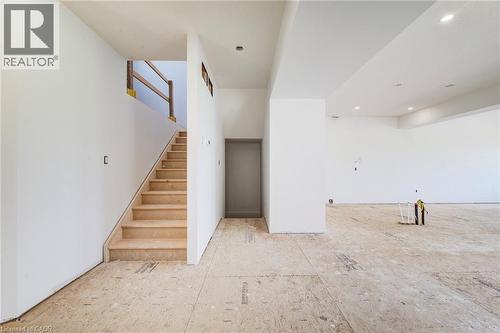 Unfinished interior space with an exposed subfloor and a central staircase featuring temporary wood railings - 114 Bedell Drive, Mapleton, ON - Indoor Photo Showing Other Room