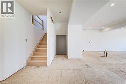 Unfinished interior space with an exposed subfloor and a central staircase featuring temporary wood railings - 