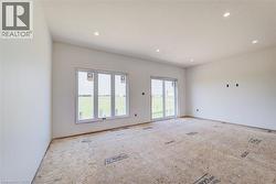 Spacious room featuring white walls, recessed ceiling lighting, a large triple window, and a sliding glass door - 