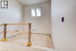 Unfinished interior space featuring a window, temporary wooden railing, and uninstalled flooring - 