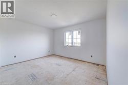 Light-filled room featuring white walls, a single window with white framing, and an overhead flush-mount light fixture - 