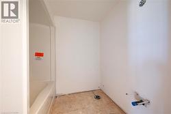 Bathroom space featuring a white acrylic bathtub and shower surround, exposed plumbing, and subfloor - 