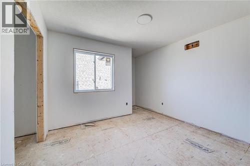 Unfinished interior space featuring a window with white framing, bare plywood subfloor, and a flush-mounted ceiling light fixture - 114 Bedell Drive, Mapleton, ON - Indoor Photo Showing Other Room