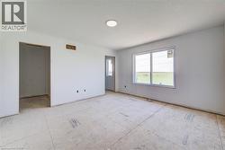 Spacious room featuring a large window, recessed lighting, white walls, and a new subfloor - 