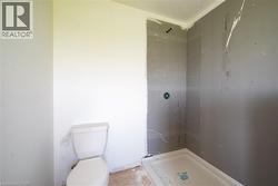 Bathroom featuring a white toilet and a shower stall with a pre-formed base - 