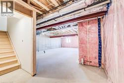 Unfinished basement offering expansive concrete flooring, exposed ceiling joists, structural steel beams, and partial insulation - 