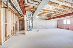 Unfinished basement featuring exposed wood framing, concrete flooring, and visible HVAC ductwork - 