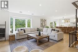 Open-concept living area featuring light wood-finish flooring, recessed lighting, and a bay window - 