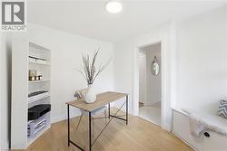 Bright interior space featuring light wood-finish flooring, white painted walls, and a white ceiling-mounted light fixture - 