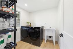 Dedicated laundry area featuring light wood-finish flooring, a utility sink with a chrome faucet, and a window with stone exterior backdrop - 