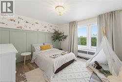 Light-filled interior featuring a double window, wood-finish flooring, a decorative wall panel, a ceiling-mounted light fixture, and light-toned window treatments - 