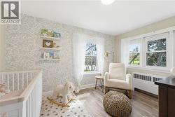 Light-filled room featuring two large windows, wood-finish flooring, and a decorative accent wall - 