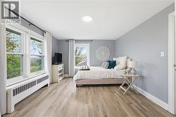 Spacious interior featuring wood-finish flooring, light grey walls, and white baseboards - 