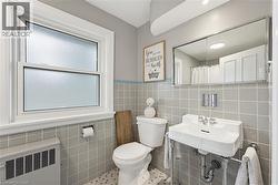 Bathroom featuring a white pedestal sink, a frosted window, a mirrored medicine cabinet, and light gray square wall tiles with a blue accent border - 