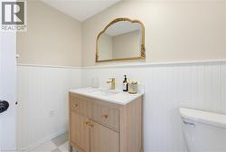 Powder room featuring a wood-finish vanity with gold-tone hardware and a white countertop - 