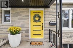 Stone veneer exterior with a vibrant yellow entry door, modern black railings, white window frames, and a recessed ceiling light - 