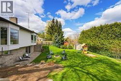 Expansive backyard featuring a manicured lawn, a built-in fire pit, and a children's play structure - 