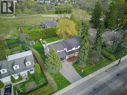 Residential property featuring mature evergreen trees, a paved driveway, and a manicured front lawn - 