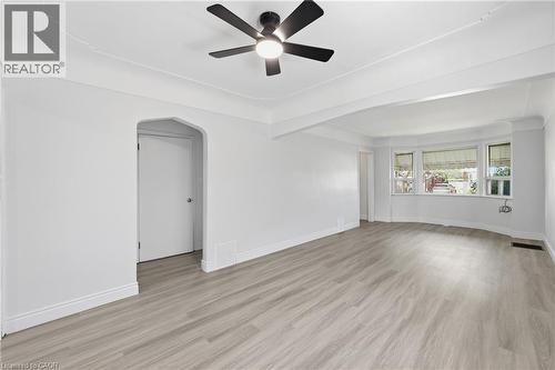 Spacious room featuring light wood-finish flooring, a contemporary ceiling fan, and a bright bay window - 97 Tragina Avenue S, Hamilton, ON 