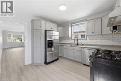 Kitchen featuring light gray cabinetry, white subway tile backsplash, stainless steel appliances, and a gas range - 