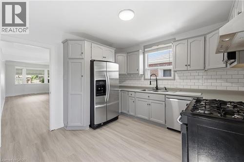 Kitchen featuring light gray cabinetry, white subway tile backsplash, stainless steel appliances, and a gas range - 97 Tragina Avenue S, Hamilton, ON 