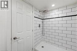 Shower with white subway tile walls, black grout, and a black accent tile stripe - 