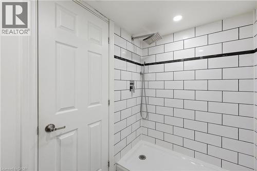 Shower with white subway tile walls, black grout, and a black accent tile stripe - 97 Tragina Avenue S, Hamilton, ON 