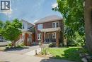 Brick exterior with white trim, a covered front porch, and a paved driveway - 41 Park Row N, Hamilton, ON 