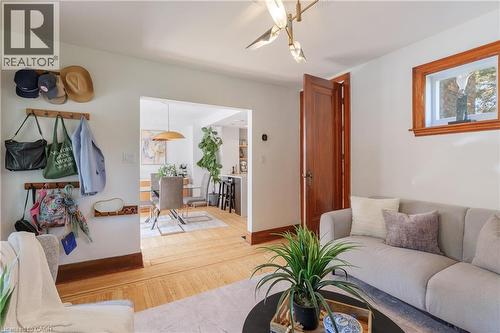 Living area featuring wood-finish flooring, a contemporary light fixture, and an archway opening to a dining space - 41 Park Row N, Hamilton, ON 