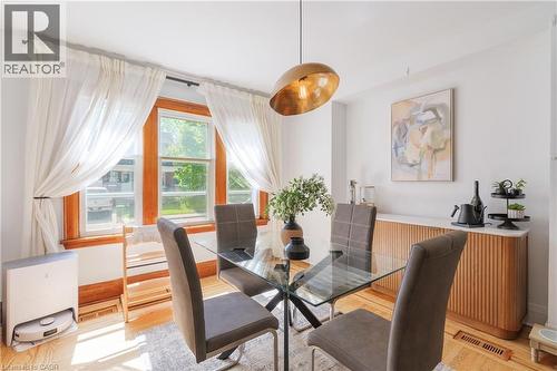 Dining area featuring wood-finish flooring and a central glass-top table with metal legs - 41 Park Row N, Hamilton, ON 