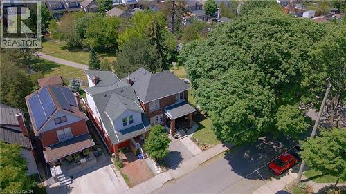 Traditional brick residence featuring a covered front porch, gabled roofline, and established front yard landscaping - 41 Park Row N, Hamilton, ON 