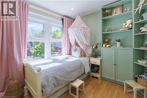Room featuring hardwood flooring, a large multi-pane window with pink drapes, and recessed ceiling lighting - 41 Park Row N, Hamilton, ON 