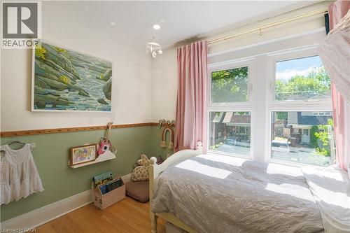 Bright room featuring a multi-pane window, wood-finish flooring, and a two-tone wall with wainscoting - 41 Park Row N, Hamilton, ON 