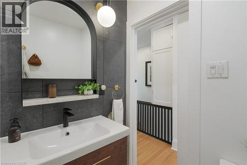 Bathroom vanity with a vessel sink, matte black faucet, and an arched mirror - 41 Park Row N, Hamilton, ON 