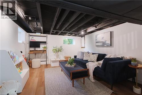 Finished basement space featuring a black exposed ceiling, recessed lighting, white walls, and wood-finish flooring - 41 Park Row N, Hamilton, ON 