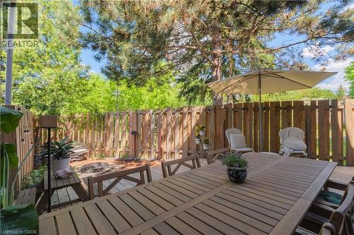 Wood deck patio with a slatted wooden table, solid wood fencing, and a built-in fire pit area - 41 Park Row N, Hamilton, ON 
