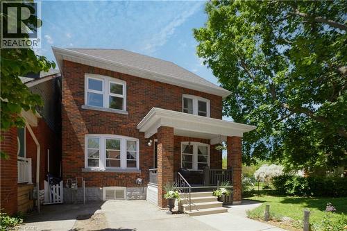 Brick facade residence featuring a covered front porch with steps and railing - 41 Park Row N, Hamilton, ON 