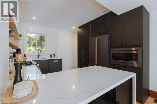Kitchen featuring a white countertop island, dark cabinetry, and integrated stainless steel appliances - 41 Park Row N, Hamilton, ON 