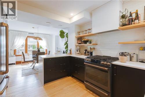Contemporary kitchen featuring dark cabinetry, light countertops, and a full suite of modern appliances - 41 Park Row N, Hamilton, ON 