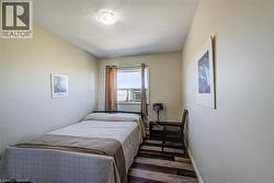 Bedroom featuring a window with a window-mounted air conditioning unit, ceiling-mounted light fixture, and multi-tone wood-finish flooring - 