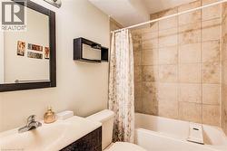 Bathroom featuring a full-sized bathtub with tiled surround, a vanity with an integrated sink, a dark framed mirror, and a wall-mounted shelving unit - 