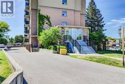 Building exterior featuring stone-clad entrance with glass doors, concrete steps, and black metal railings - 