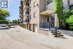 Brick facade building featuring individual garages, multiple balconies with glass railings, and a main entrance with concrete steps and black metal railings - 